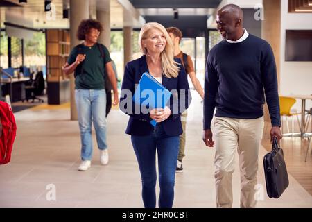 Male And Female Tutors In Busy University Or College Building With Students Stock Photo