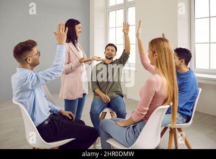 Young people sitting on chairs in circle having fun talking during informal brainstorming session. Stock Photo