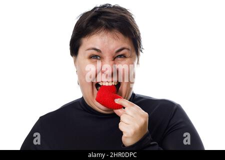 brunette woman puts red heart in her mouth isolated on white background Stock Photo