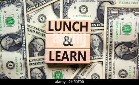 Lunch and learn symbol. Concept words Lunch and learn on wooden blocks. Beautiful background from dollar bills. Copy space. Business, educational and Stock Photo