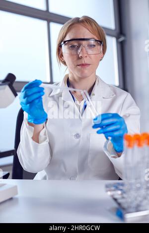 Female Lab Worker Wearing White Coat Using Pipette And Test Tube In Research Stock Photo