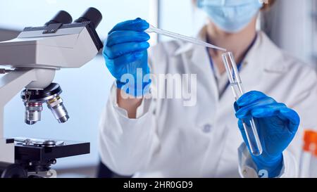 Close Up Of Female Lab Worker Wearing White Coat Using Pipette And Test Tube In Research Stock Photo