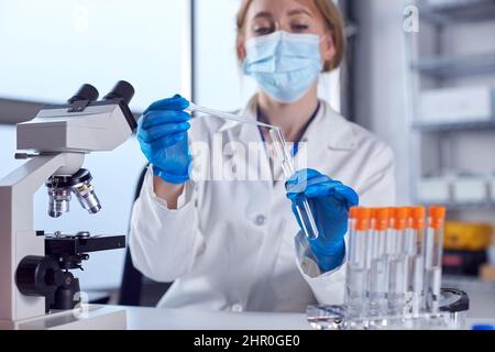 Female Lab Worker Wearing White Coat Using Pipette And Test Tube In Research Stock Photo