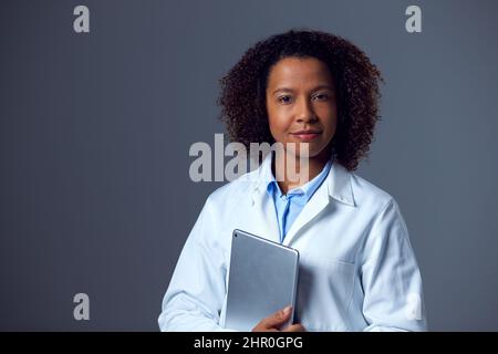 Studio Portrait Of Female Doctor In Lab Coat Holding Digital Tablet Stock Photo