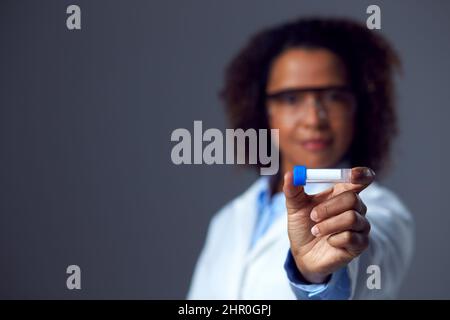 Female Doctor Or Lab Worker Wearing PPE And Safety Glasses Holding Vial Or Test Tube Stock Photo
