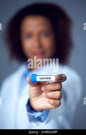 Female Lab Research Worker Wearing Lab Coat Holding Test Tube Labelled Vaccine Stock Photo