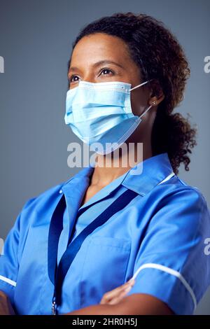 Studio Portrait Of Female Nurse Wearing Uniform And Face Mask Stock Photo
