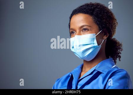 Studio Portrait Of Female Nurse Wearing Uniform And Face Mask Stock Photo