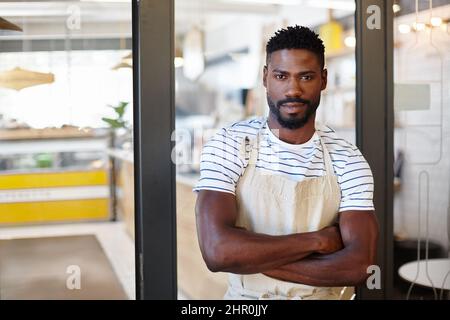 We make seriously good coffee in here. Portrait of a handsome young man standing at the entrance to his coffee shop. Stock Photo