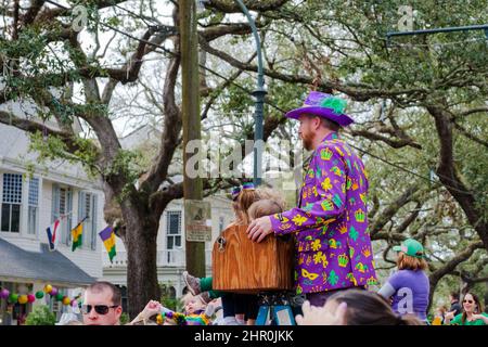 NEW ORLEANS, LA, USA - FEBRUARY 20, 2022: Colorfully dressed man on a ladder with his children along the Krewe of Femme Fatale Mardi Gras parade route Stock Photo