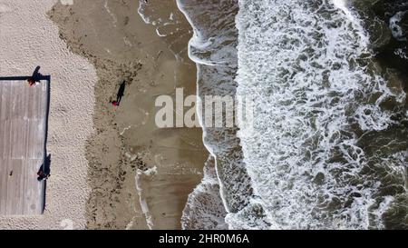 People walking and relaxing on beach on sunny day. Aerial Drone View Flight Over Stock Photo