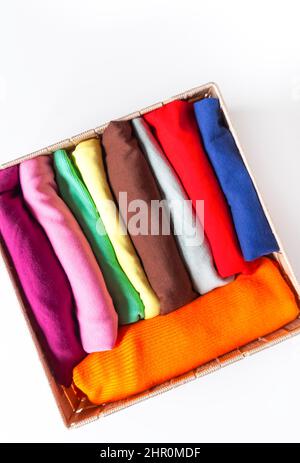 Folded colorful clothes in the box. Home organizing. Domestic vertical storage. Stock Photo
