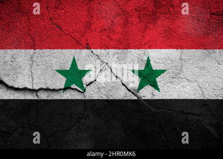 Full frame photo of a weathered flag of Syria painted on a cracked wall. Stock Photo
