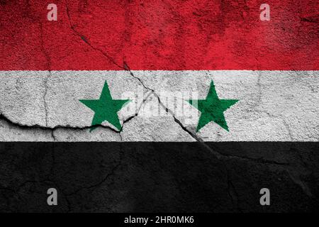 Full frame photo of a weathered flag of Syria painted on a cracked wall. Stock Photo