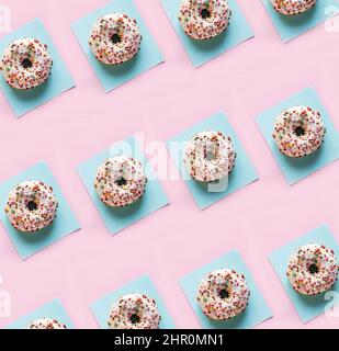Delicious glazed donuts on the pink table background. Repeating pattern, top view, close up. Stock Photo