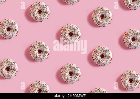 Delicious glazed donuts on the pink table background. Repeating pattern, top view, close up. Stock Photo