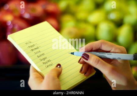 I love making lists. Cropped image of a womans hand holding a shopping list. Stock Photo