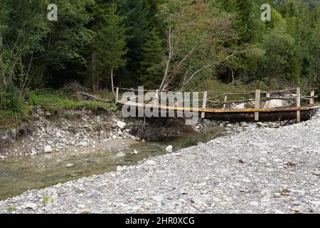 Small mountain river rushing along the stone bottom, rocky shore. Bridge over a mountain river. Stock Photo