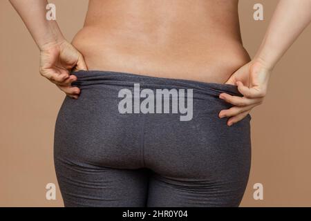https://l450v.alamy.com/450v/2hr0y04/closeup-of-lady-with-large-sides-with-hands-pulling-up-leggings-pants-on-beige-background-body-positive-accepting-who-you-are-tight-clothes-need-2hr0y04.jpg