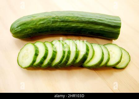 Whole and Sliced Cucumbers on a Wooden Cutting Board Stock Photo