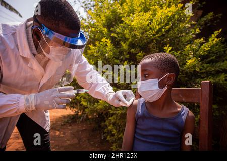 A doctor in africa vaccinates a child. Doctor injects coronavirus vaccine to a kid in Africa Stock Photo