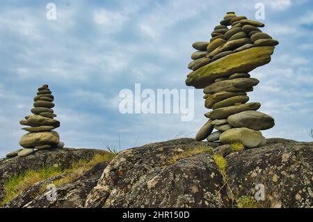Two cairns made of well-balanced smooth stones on a weathered boulder Stock Photo