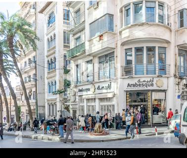people wearing masks waiting in queue for Arabesque Restaurant in Victor Hugo street, Algiers city. Restaurant and food nameplate  Arabic and French. Stock Photo