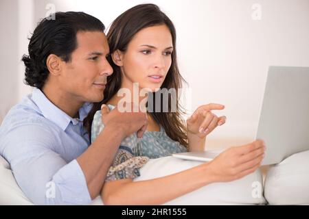 What do you think. A husband and wife browsing the web while sitting together on the sofa. Stock Photo