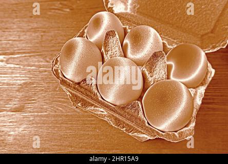 Pop Art Style Rose Gold Colored Chicken Eggs in a Carton Box Isolated on Wooden Backdrop Stock Photo
