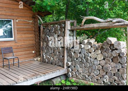 Firewood for the sauna stove, saunas are stacked next to the wooden rural bath. For lifestyle design. There is a row of firewood against the wall. Rur Stock Photo