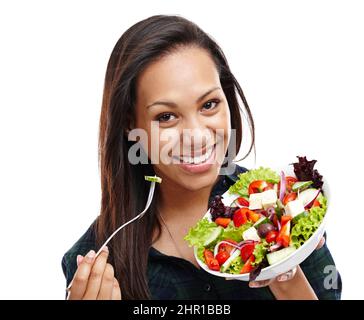 Making the healthy choice. Portrait of an attractive young woman enjoying a bowl of salad isolated on white. Stock Photo