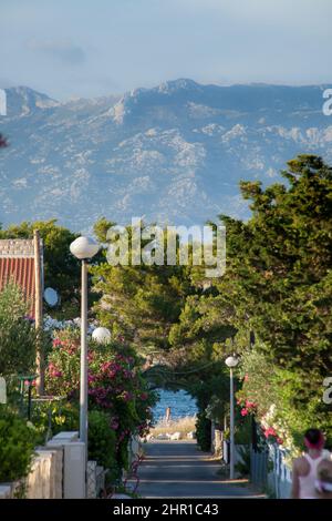 A small alley towards the sea in the apartment complex Lučica on the island of Vir, Croatia. View of the sea and the mountains. Stock Photo