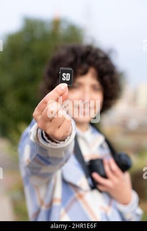 Curly hair woman showing an sd memory card to the camera Stock Photo