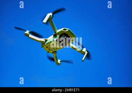 Drone flying overhead in cloudy blue sky Stock Photo