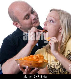 couple enjoys a cozy evening watching TV with a bowl of chips Stock Photo
