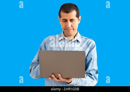 Cropped portrait of handsome young businessman working on his laptop with blue background Stock Photo