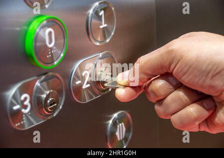 Elevator access control. hand holding a key to unlock elevator floor Stock Photo