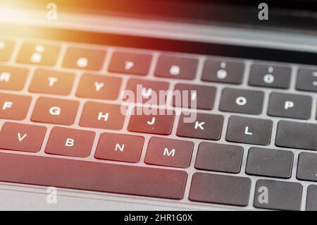 Keyboard in side angle focused on the letter M. Keyboard in shades of gray and black with sunlight Stock Photo