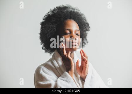 The happy woman is smearing her face with moisturizer Stock Photo