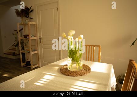 Spring flowers - white tulips in glass vase on wooden table Stock Photo