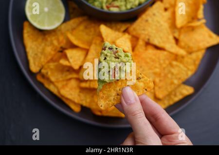 Closeup of woman hand with nachos and fresh tasty guacamole dip Stock Photo