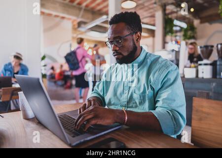young black man working on laptop in coffee shop Stock Photo