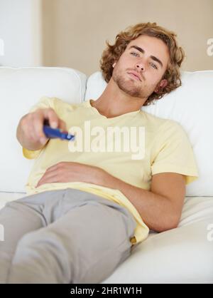 Chilling. A lazy young man flicking through TV channels. Stock Photo