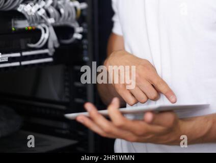 Getting you back online. A computer technician browsing the internet on his digital tablet. Stock Photo