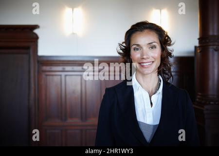 Cropped shot of an attractive mature female lawyer standing in a courtroom and smiling. Cropped shot of an attractive mature female lawyer standing in Stock Photo
