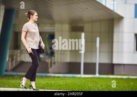 young woman walks through a green city on a summer day. full body Stock Photo