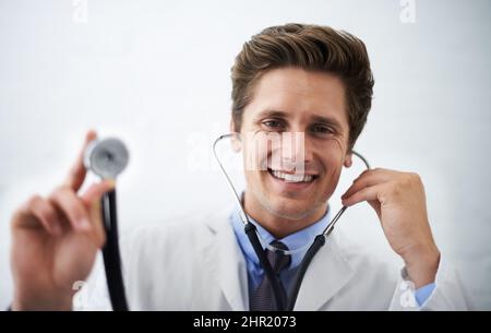 This is going to feel cold. Shot of a positive-looking doctor holding up the end of a stethoscope toward the camera. Stock Photo