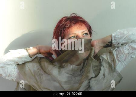 playful caucasian young adult redhead woman having fun in the studio a sunny day Stock Photo