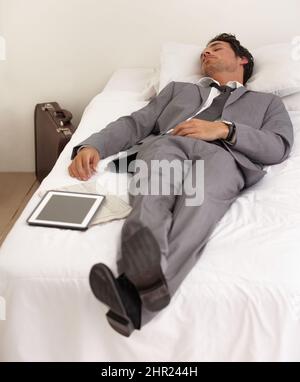 Work exhaustion. A handsome young businessman sleeping on the bed with his digital tablet. Stock Photo
