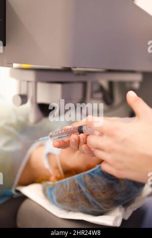 Detail of a doctor holding a syringe during a surgery Stock Photo